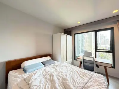 Modern bedroom with city view, featuring a cozy bed and stylish workspace.