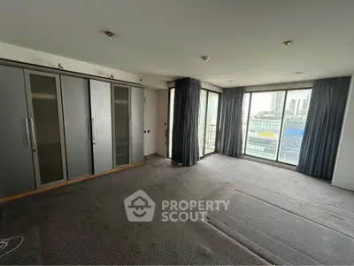 Spacious bedroom with large windows and city view, featuring built-in wardrobes and modern design.