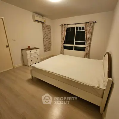 Cozy bedroom with minimalist decor and natural light, featuring a comfortable bed and stylish curtains.