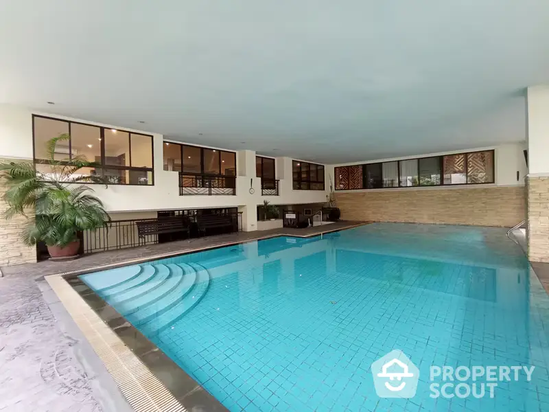 Luxurious indoor swimming pool with elegant design, surrounded by large windows and comfortable seating areas, perfect for upscale living.