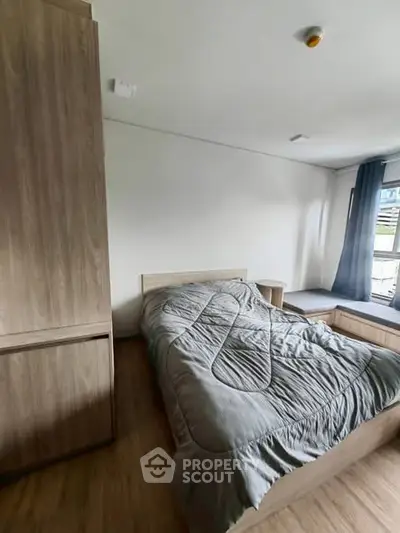 Cozy bedroom with modern wooden furniture and large window for natural light.