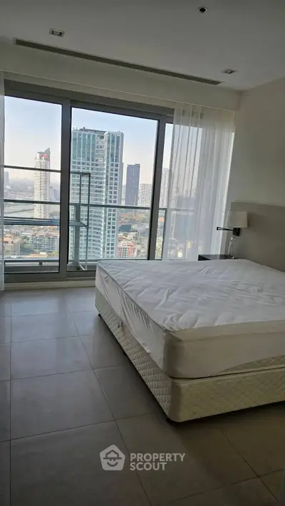 Spacious bedroom with stunning city view and large windows in modern high-rise apartment.