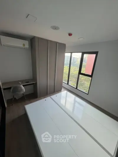 Modern bedroom with large window and built-in wardrobe, featuring a sleek air conditioning unit.