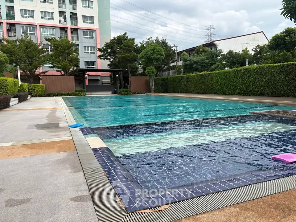 Luxurious outdoor pool area with lush greenery and modern apartment building backdrop.