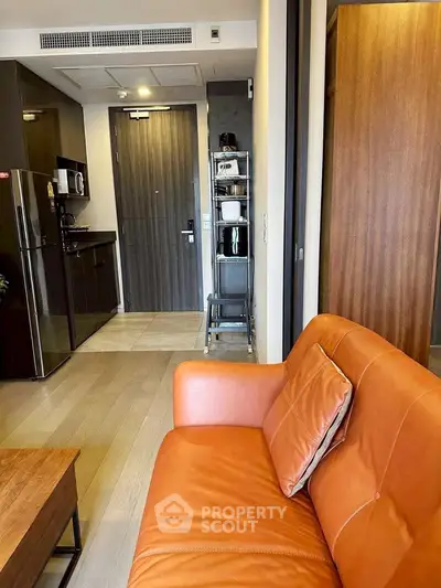 Modern apartment interior with stylish orange sofa and compact kitchen area, perfect for urban living.