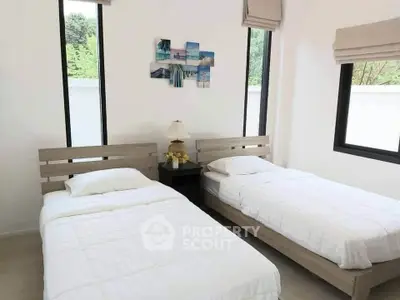 Bright bedroom with twin beds and large windows offering garden views.