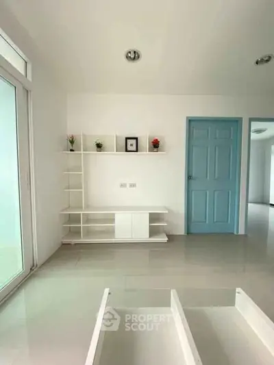Bright minimalist living room with blue door and modern shelving unit