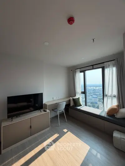 Modern living room with large window and city view, featuring sleek furniture and natural light.