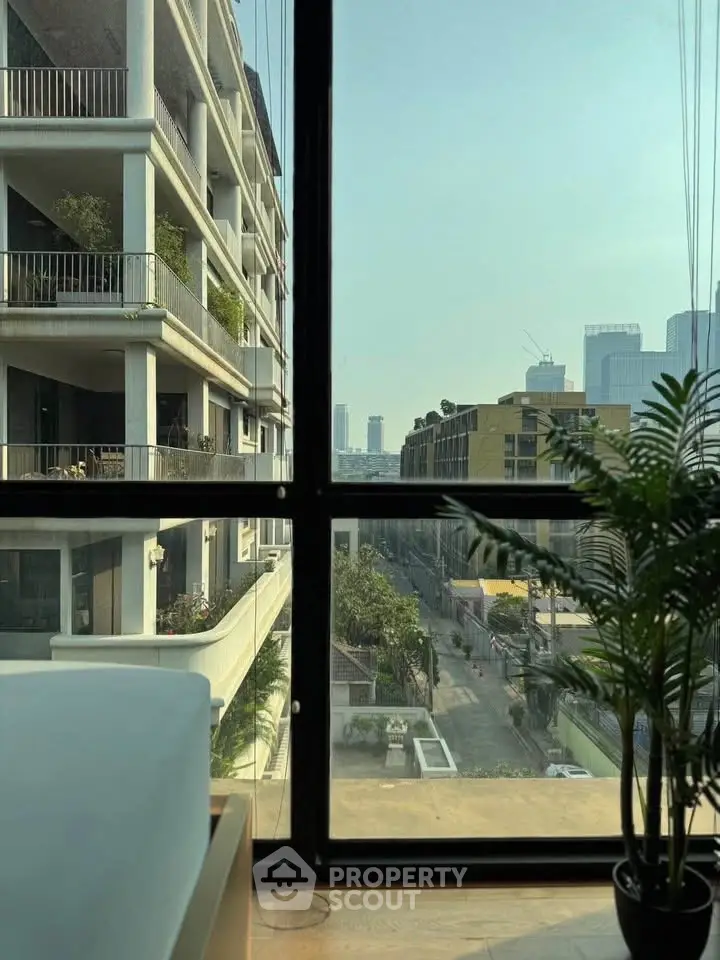 Modern apartment with large windows offering stunning city views and lush greenery.