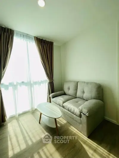 Bright living room with cozy sofa and natural light through large window, perfect for relaxation.