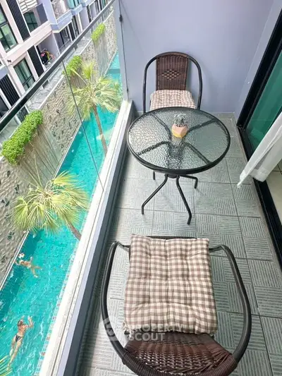 Chic balcony overlooking pool with stylish seating and glass railing