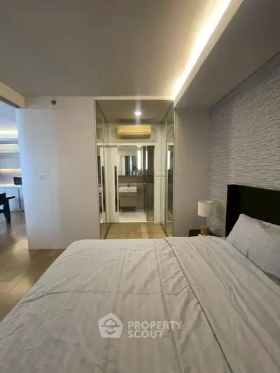 Modern bedroom with mirrored closet and stylish lighting in a contemporary apartment.