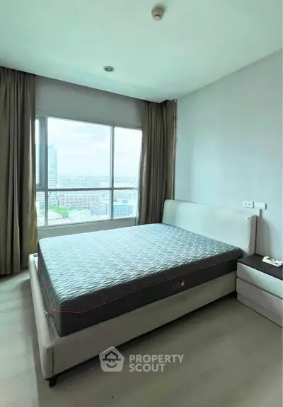 Spacious bedroom with large window offering stunning city views in modern apartment.