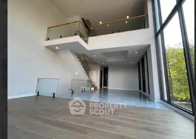 Stunning modern duplex with floor-to-ceiling windows and elegant staircase.