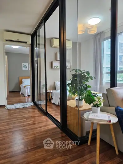 Modern apartment with glass partition, cozy living area, and stylish bedroom.