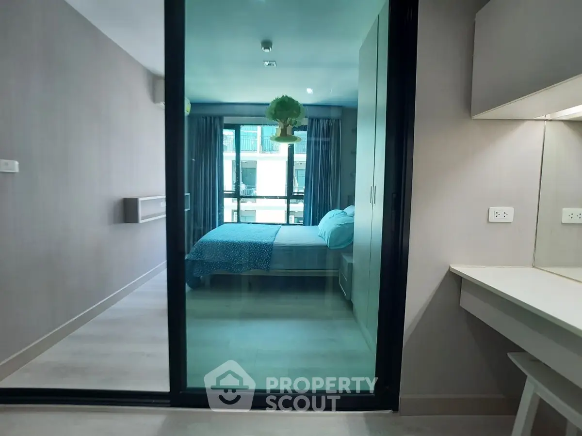 Modern bedroom with glass sliding door and stylish decor in a contemporary apartment.