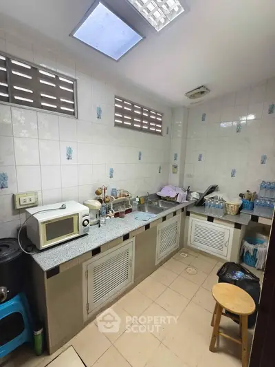Cozy kitchen with tiled walls, skylights, and modern appliances in a compact layout.
