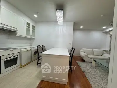 Modern open-layout kitchen with dining area and cozy living room featuring elegant lighting.