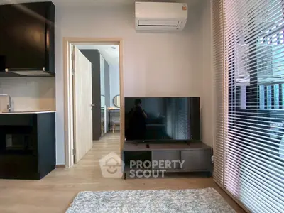 Modern living room with sleek TV setup and air conditioning, adjacent to a stylish kitchen area.