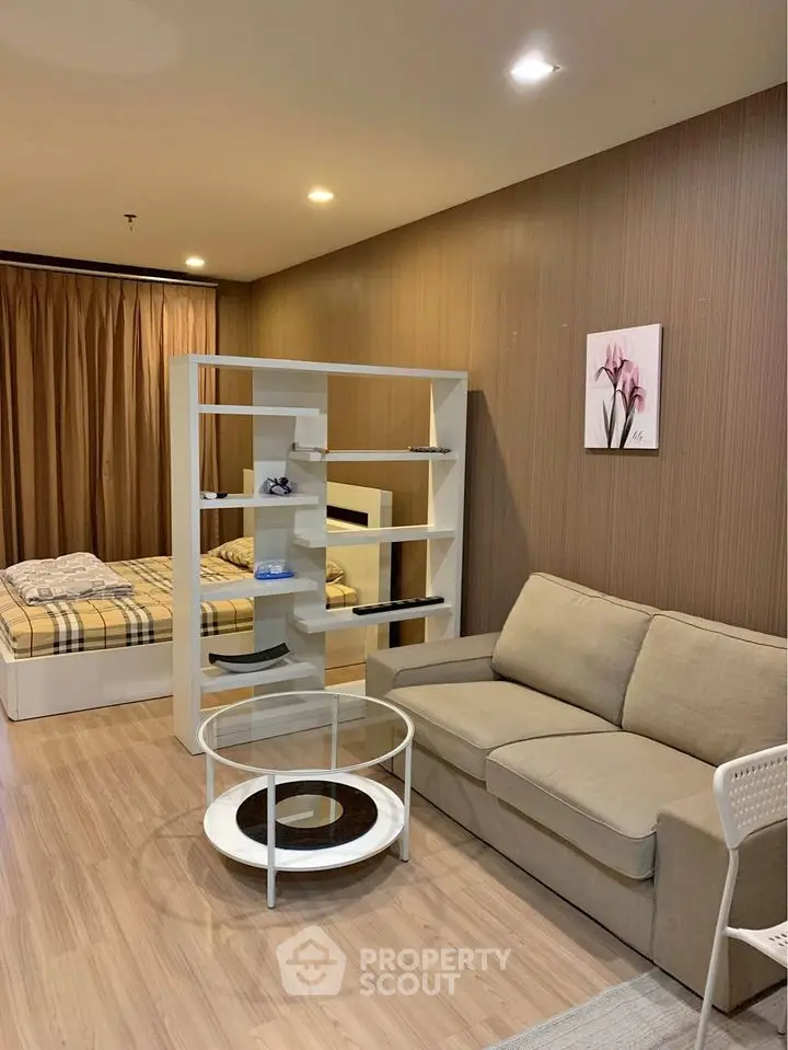 Modern studio apartment with an open layout featuring a cozy living area and a comfortable bedroom space, separated by a stylish shelving unit.