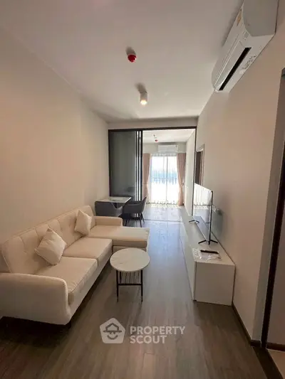 Modern living room with sleek furniture and natural light, featuring a cozy sofa and flat-screen TV.