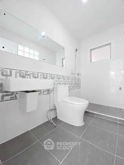 Modern bathroom with sleek white fixtures and stylish gray tile flooring.