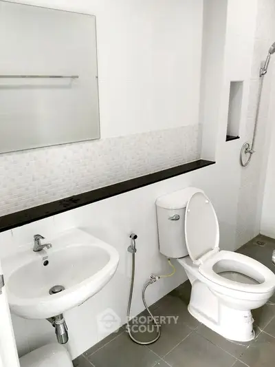 Modern bathroom with sleek fixtures and minimalist design, featuring a shower and toilet.
