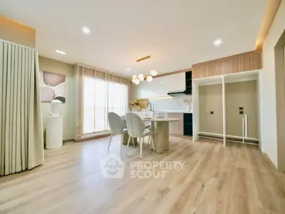 Spacious modern kitchen with open layout and elegant dining area, featuring stylish lighting and wooden flooring.