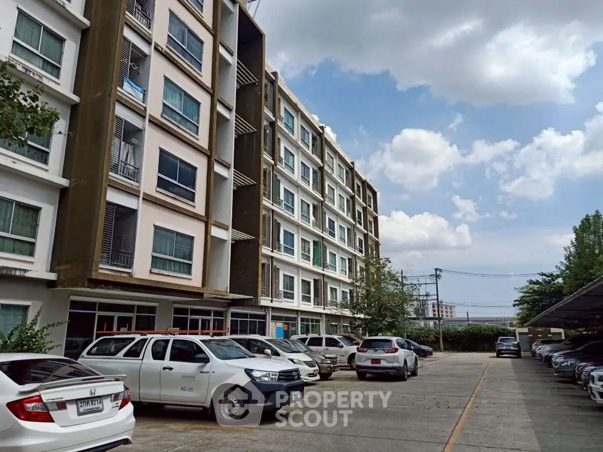 Modern apartment building with spacious parking area under a clear blue sky.