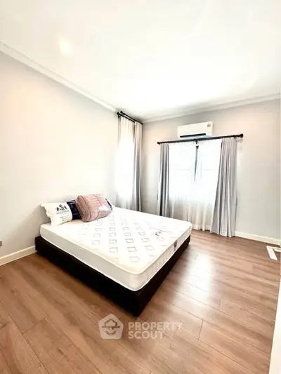 Bright and airy bedroom with wooden flooring and large windows