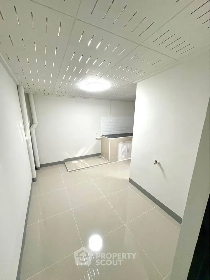 Spacious basement area with tiled flooring and utility sink, ideal for storage or laundry setup.