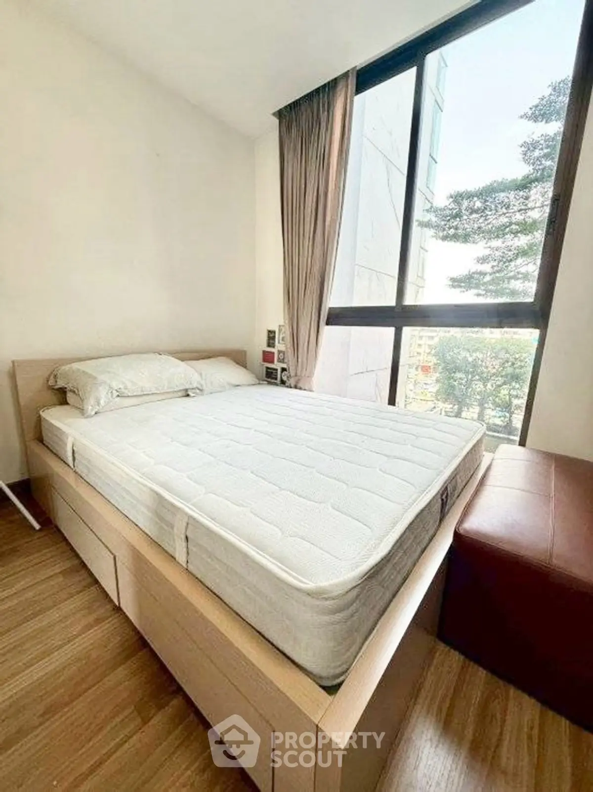 Cozy bedroom with large window and wooden flooring, perfect for natural light lovers.