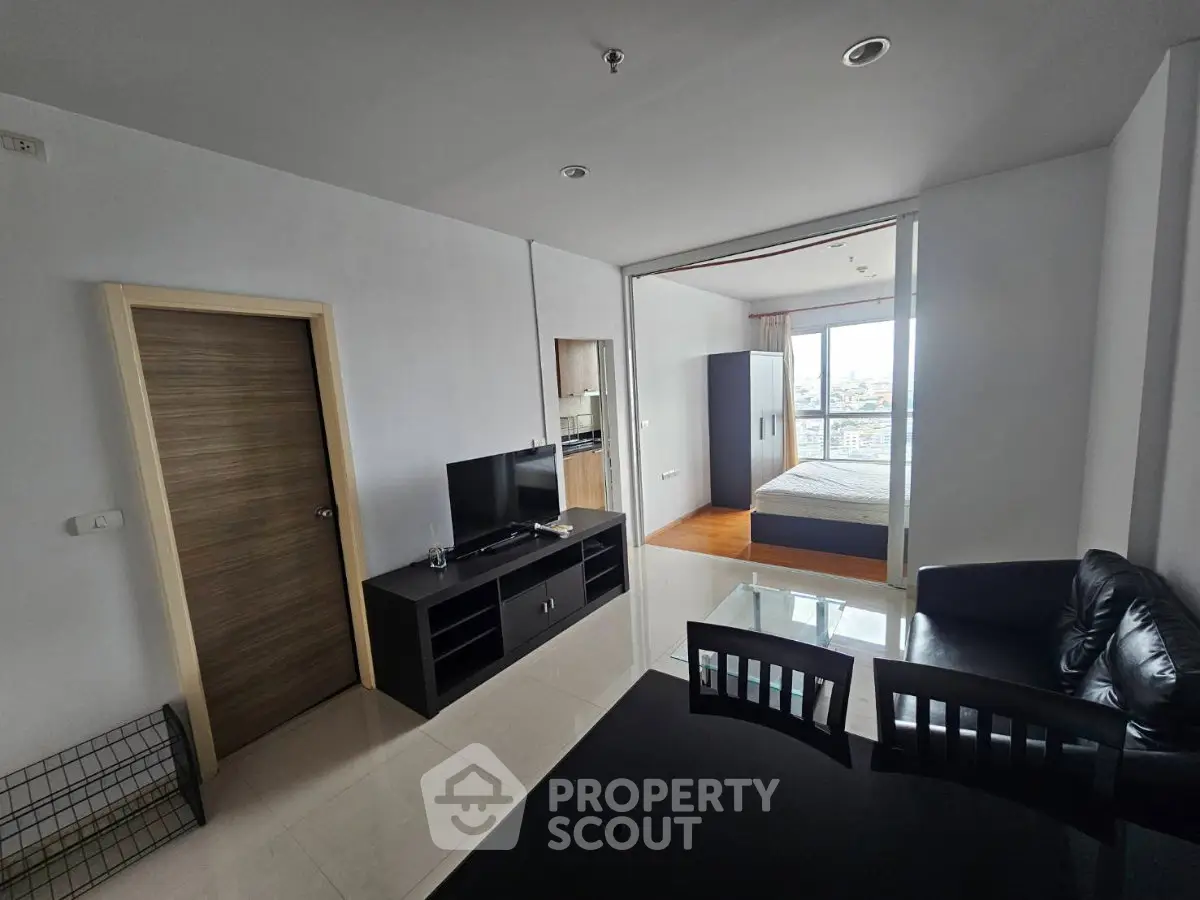 Modern apartment interior with open living room and bedroom, featuring sleek furniture and city view.