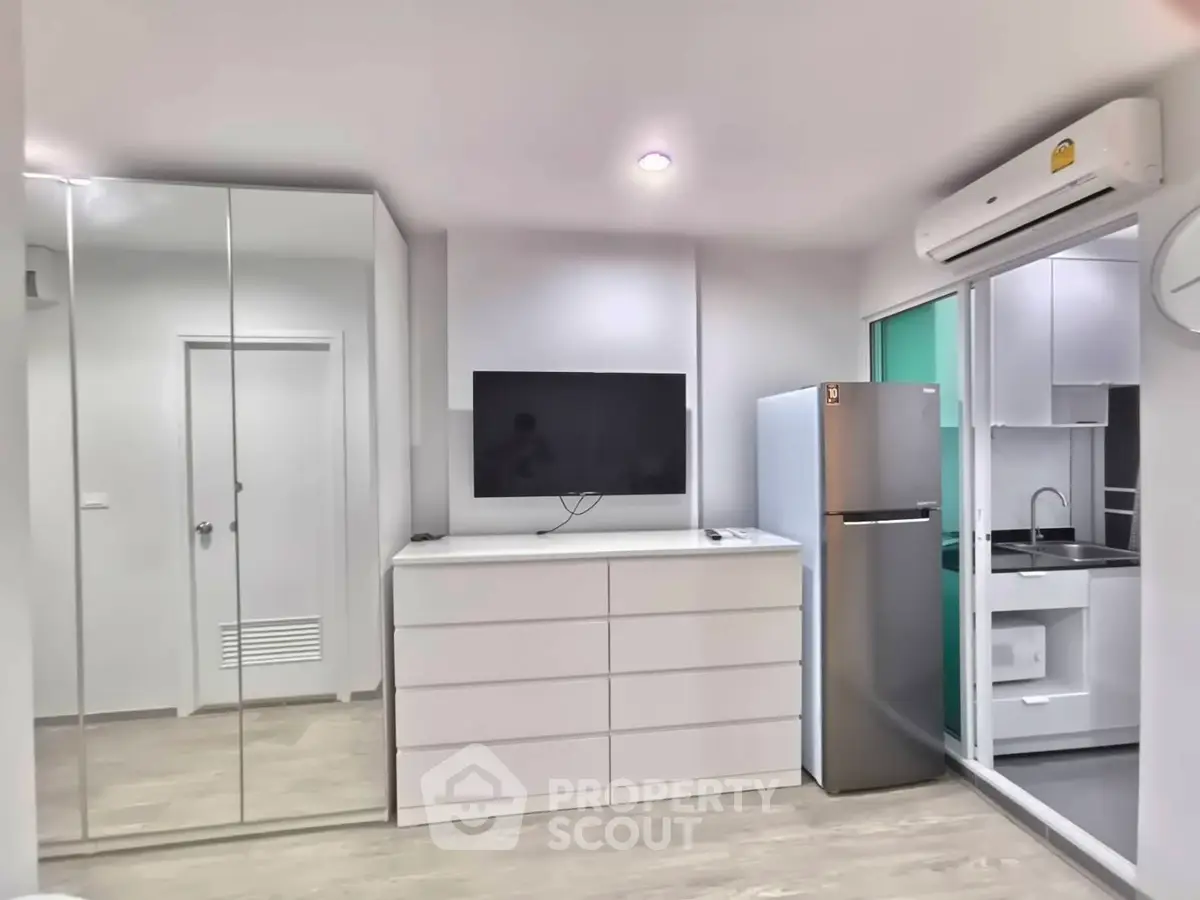 Modern apartment interior with mirrored closet and sleek kitchen appliances