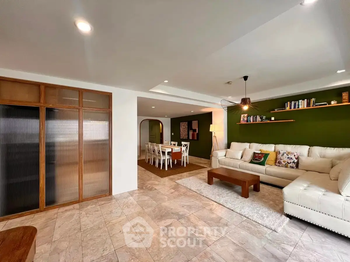 Spacious living room with modern decor and dining area, featuring elegant lighting and stylish furnishings.