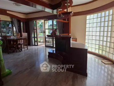 Spacious living room with elegant wooden accents and large windows offering garden views.