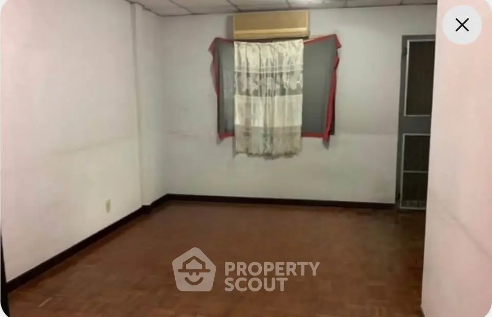 Spacious empty room with parquet flooring and air conditioning unit.