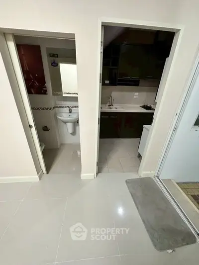 Modern apartment interior with kitchen and bathroom view, sleek design and tiled flooring.
