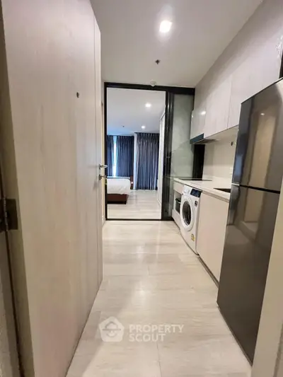 Modern apartment hallway with kitchen and laundry area leading to bedroom