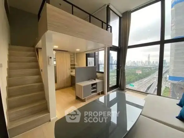 Modern loft apartment with large windows and city view, featuring a cozy living area and mezzanine.