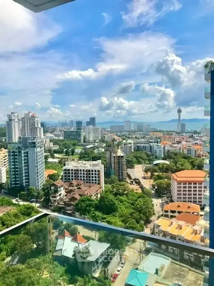 Stunning cityscape view from high-rise balcony with lush greenery and urban skyline.