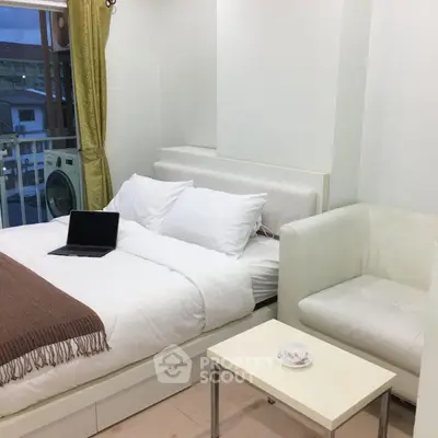 Cozy bedroom with modern decor and city view, featuring a comfortable bed and stylish seating area.