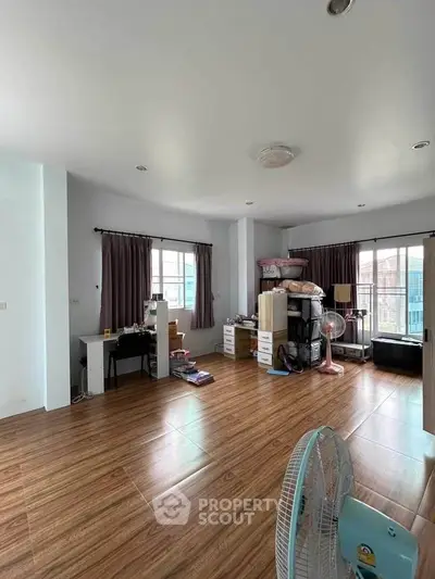 Spacious living room with wooden flooring and ample natural light.