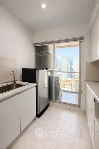 Modern kitchen with sleek cabinetry and balcony view in urban apartment