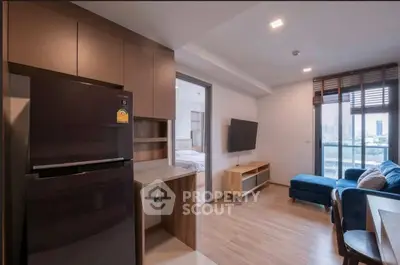 Modern open-plan living room with sleek kitchen and city view, featuring stylish furniture and natural light.