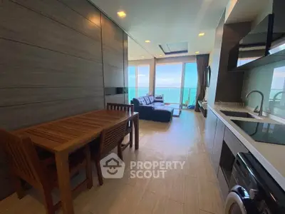Modern open-plan living room with ocean view, sleek kitchen, and cozy dining area in luxury apartment.