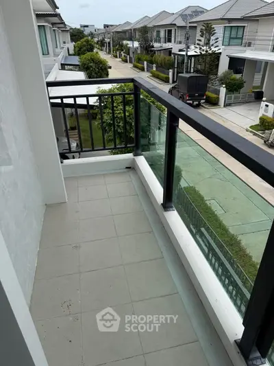 Charming balcony with glass railing offering a serene neighborhood view in a modern residential area.