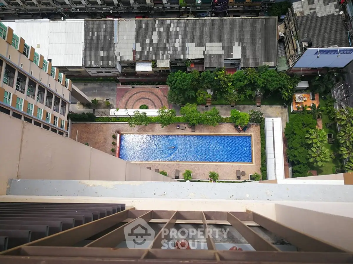 Stunning aerial view of a modern apartment complex with a sparkling swimming pool and lush greenery.