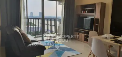 Spacious living room with modern furniture, natural light, and a large balcony offering a stunning city view, perfect for urban living.