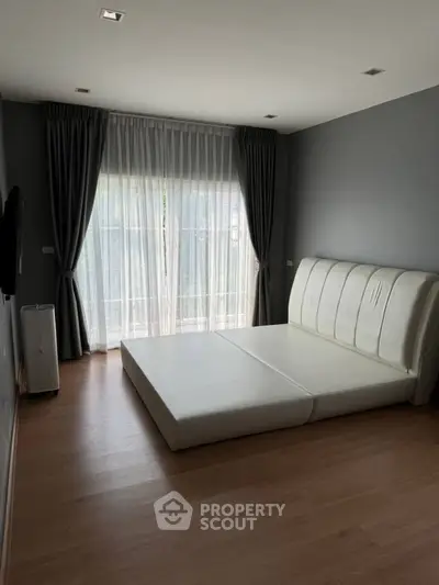 Spacious bedroom with modern minimalist design and large window for natural light.